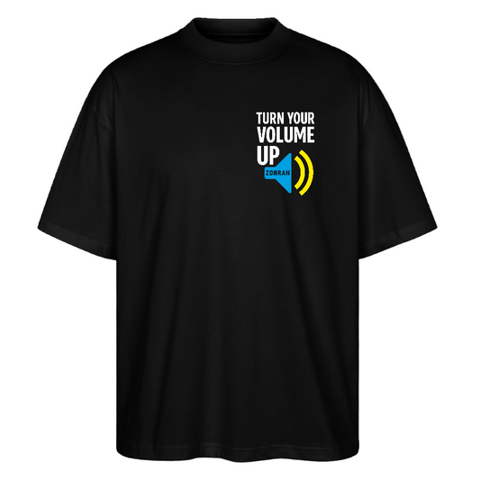 Front on black tee: "Black oversized unisex t-shirt with white TURN YOUR VOLUME UP chest print and blue ZDRAM speech bubble with yellow sound waves"